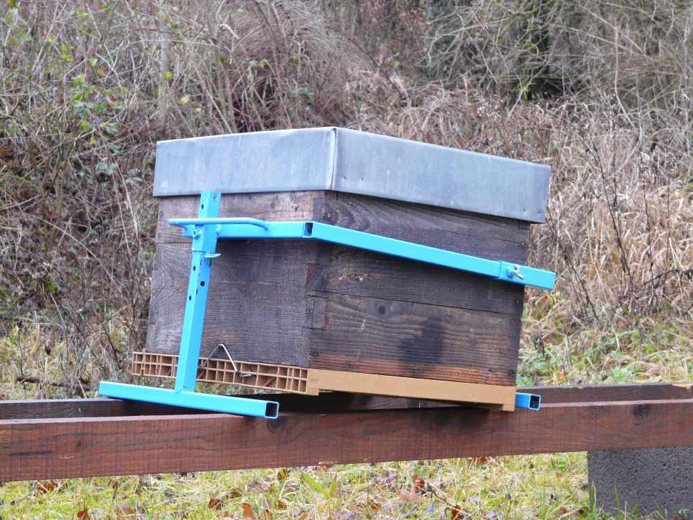 Soulever un coté de la ruche et bloquer le pied avec la goupille